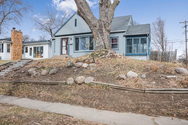 view of front of home with fence and roof with shingles