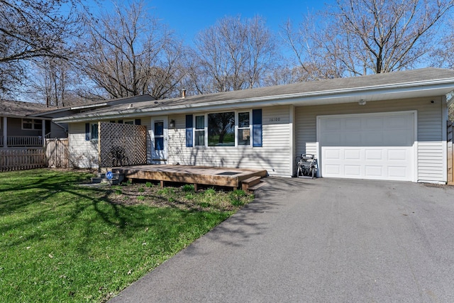 ranch-style home with a garage, aphalt driveway, a wooden deck, fence, and a front yard