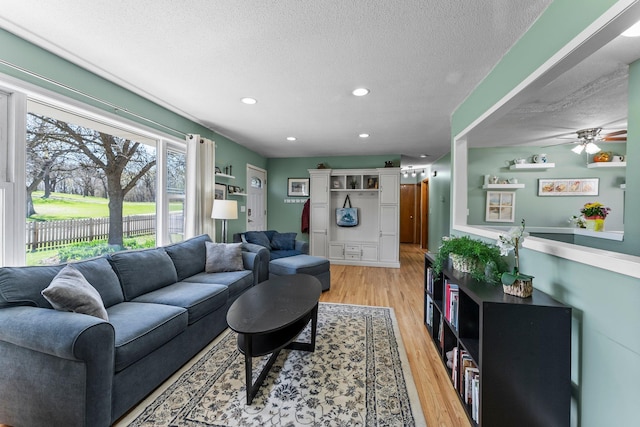 living room featuring recessed lighting, a textured ceiling, ceiling fan, and light wood-style flooring