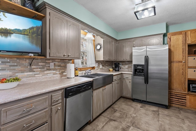 kitchen with light countertops, a sink, appliances with stainless steel finishes, and tasteful backsplash