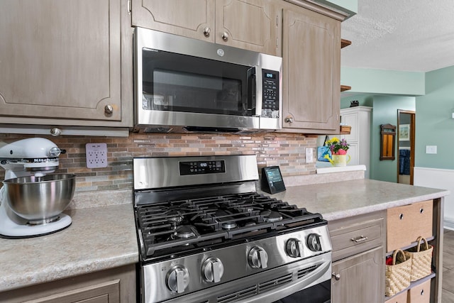 kitchen with light countertops, a textured ceiling, backsplash, and stainless steel appliances