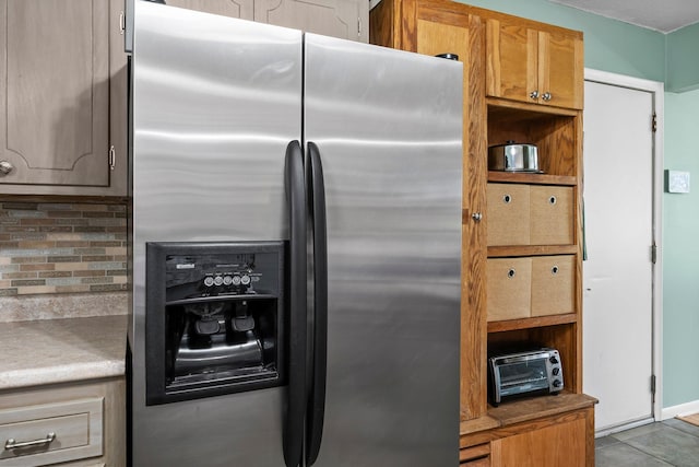 kitchen featuring a toaster, tile patterned floors, tasteful backsplash, and stainless steel refrigerator with ice dispenser
