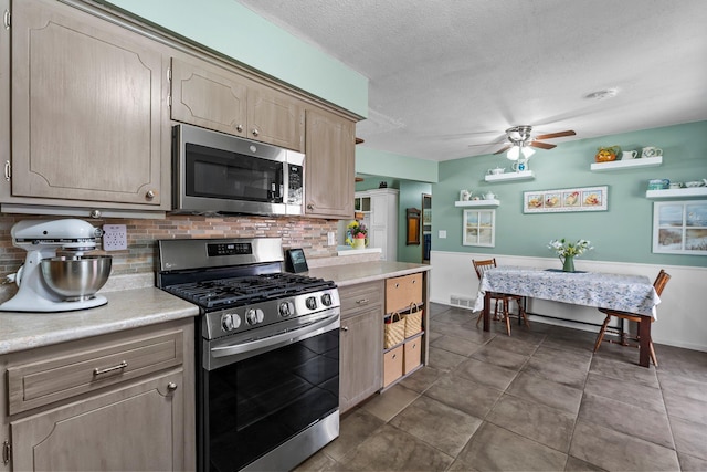 kitchen with a ceiling fan, backsplash, a textured ceiling, appliances with stainless steel finishes, and light countertops