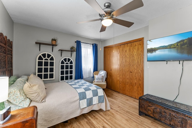 bedroom with light wood-style floors, ceiling fan, and a closet
