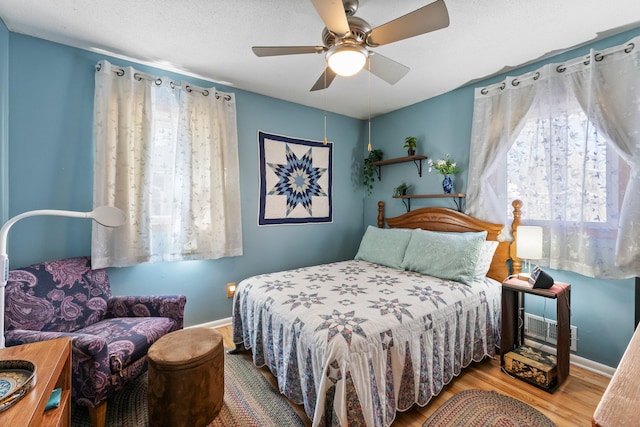 bedroom with baseboards, multiple windows, and wood finished floors