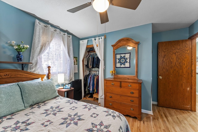 bedroom with a closet, a ceiling fan, baseboards, and wood finished floors