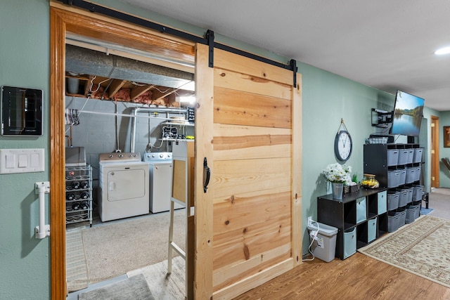 interior space with wood finished floors, a barn door, and washing machine and dryer