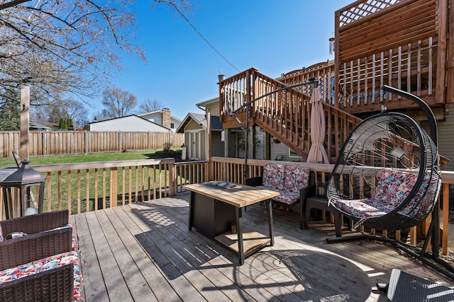 wooden deck with a fenced backyard, a storage unit, an outbuilding, a yard, and stairway