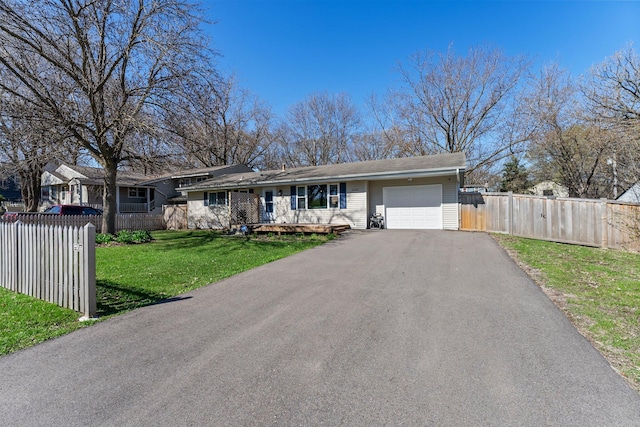 ranch-style house featuring a garage, fence, a front lawn, and aphalt driveway