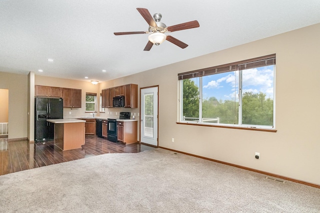 657 Golden Oak St NE, Lonsdale, MN 55046 - kitchen with black appliances, dark colored carpet, light countertops, a kitchen island, and open floor plan