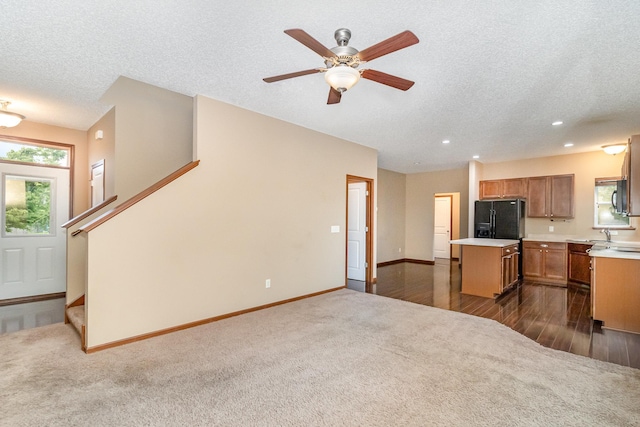 657 Golden Oak St NE, Lonsdale, MN 55046 - kitchen featuring black refrigerator with ice dispenser, a kitchen island, light countertops, dark carpet, and ceiling fan