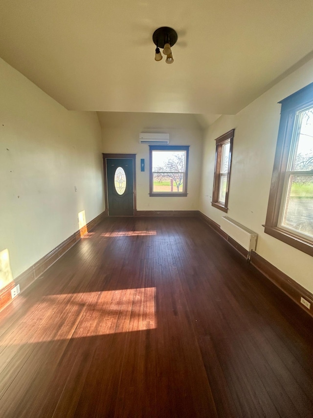 interior space featuring baseboards, radiator heating unit, a wall unit AC, and dark wood-style floors