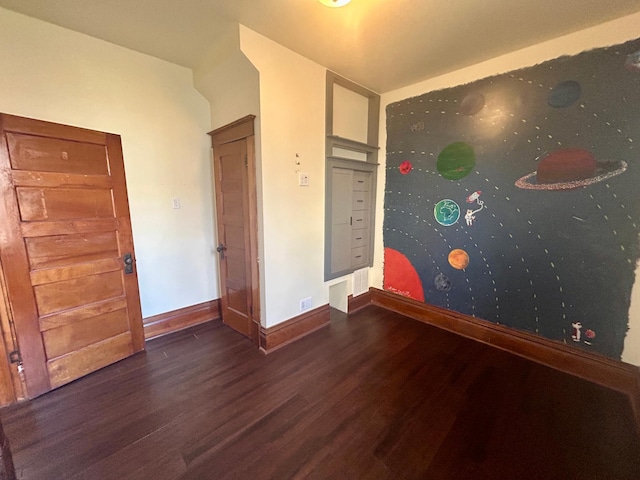 spare room featuring wood finished floors and baseboards