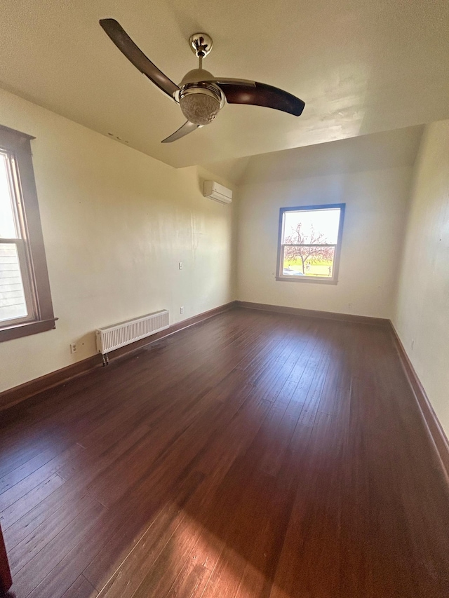 unfurnished room featuring a ceiling fan, dark wood-style floors, and a wall unit AC