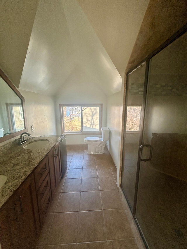 bathroom featuring vaulted ceiling, a sink, a stall shower, double vanity, and tile patterned flooring