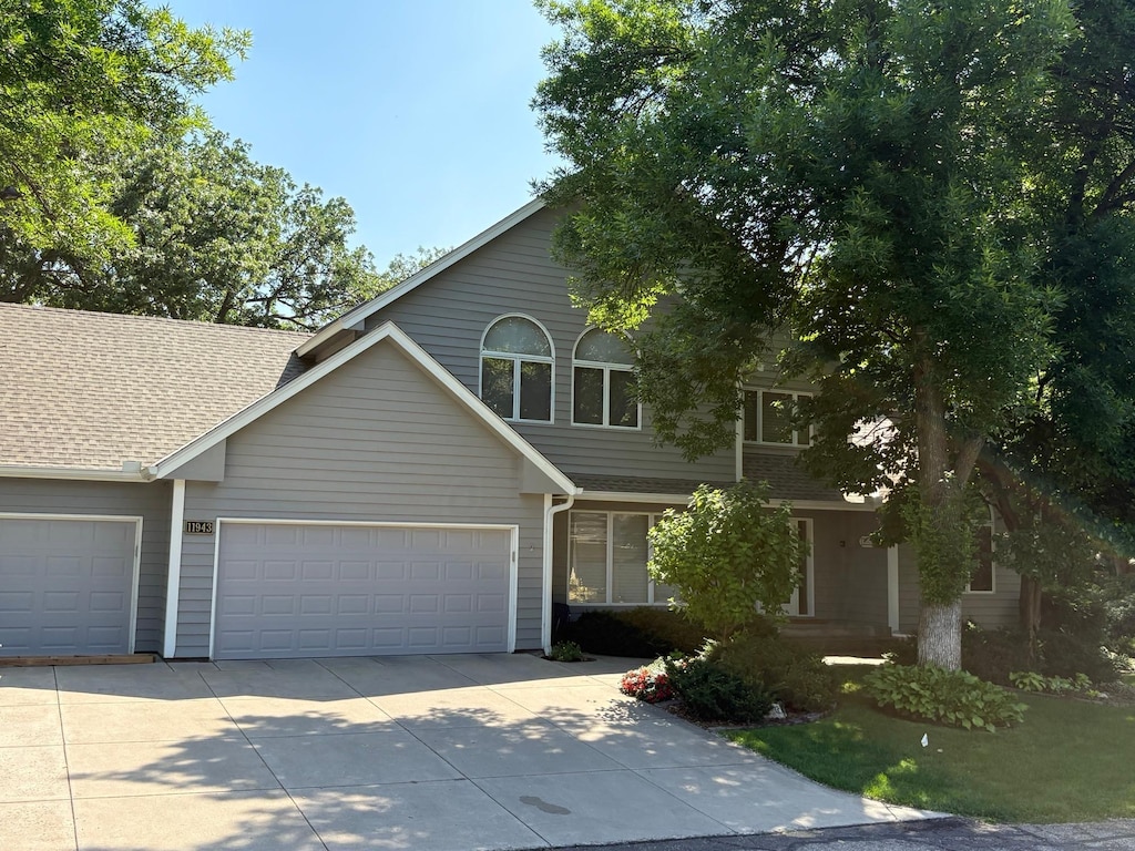 11943 Orchard Ave W, Minnetonka, MN 55305 - view of front facade featuring driveway, an attached garage, and roof with shingles