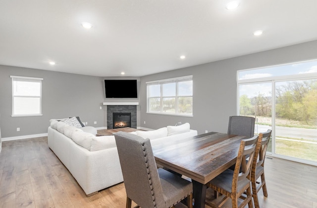 3088 Sunflower Way NW, Prior Lake, MN 55352 - dining space featuring a glass covered fireplace, recessed lighting, light wood-type flooring, and baseboards