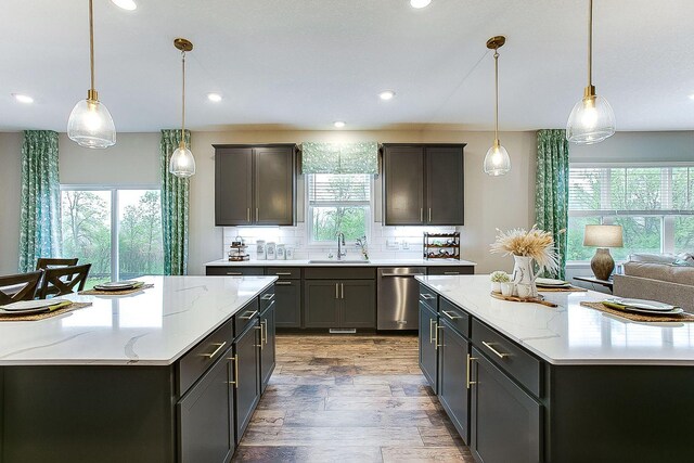 kitchen featuring recessed lighting, wood finished floors, a spacious island, dishwasher, and a sink