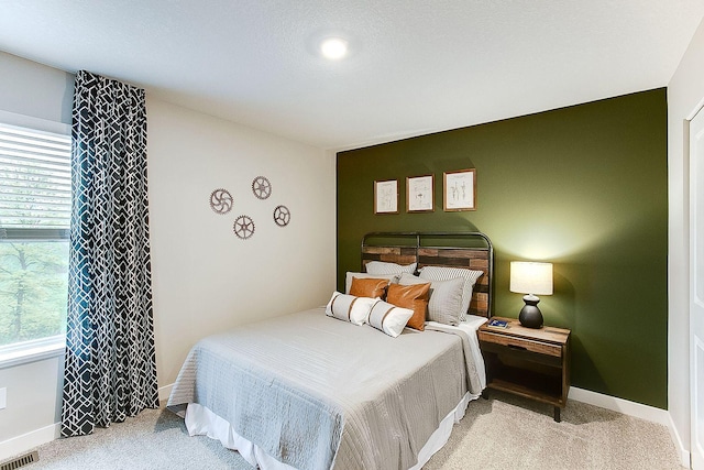 bedroom featuring baseboards, visible vents, light carpet, and multiple windows