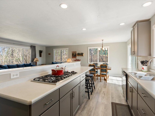 kitchen with a sink, gray cabinets, stainless steel gas cooktop, and plenty of natural light