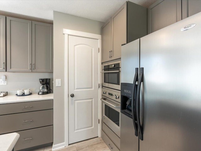 kitchen with light countertops, appliances with stainless steel finishes, gray cabinets, and light wood-type flooring
