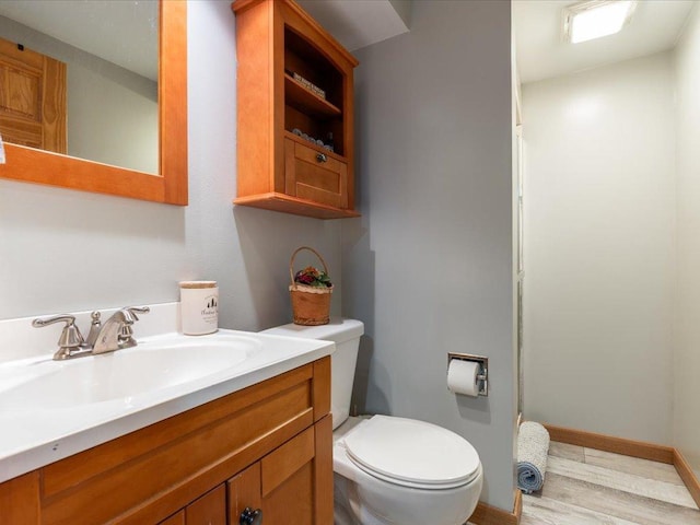 bathroom featuring vanity, baseboards, toilet, and wood finished floors