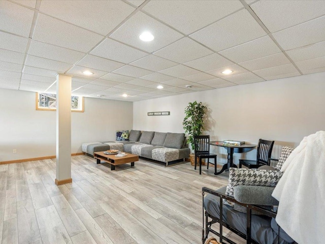 living room featuring baseboards, a drop ceiling, and light wood-style flooring