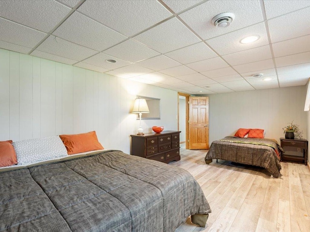 bedroom with a drop ceiling and wood finished floors