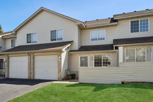 townhome / multi-family property featuring roof with shingles, an attached garage, driveway, and a front lawn