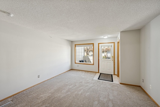 entrance foyer featuring baseboards, a textured ceiling, and light carpet