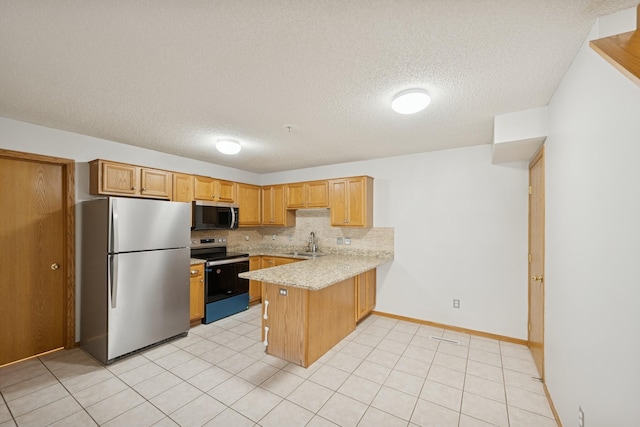 kitchen featuring a textured ceiling, a sink, light countertops, a peninsula, and stainless steel appliances