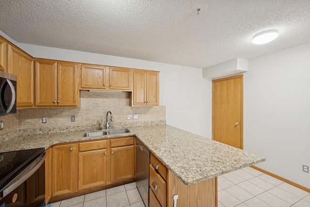kitchen with backsplash, a sink, a peninsula, stainless steel appliances, and light tile patterned flooring