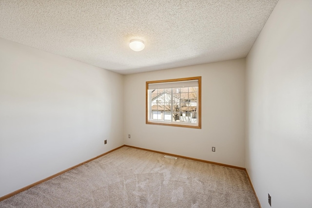 spare room with a textured ceiling, visible vents, baseboards, and carpet
