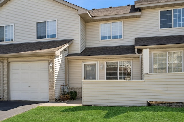 view of front facade with a shingled roof, an attached garage, and a front yard
