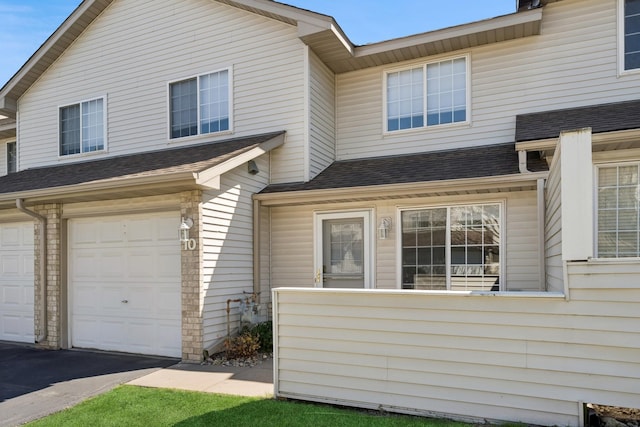 view of front of home featuring a garage and a shingled roof