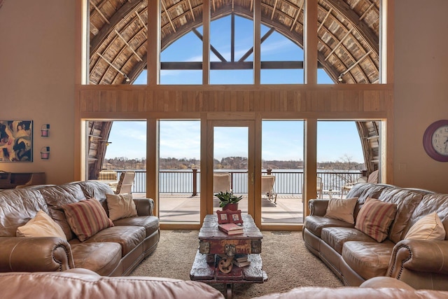 living area with high vaulted ceiling, a water view, and plenty of natural light