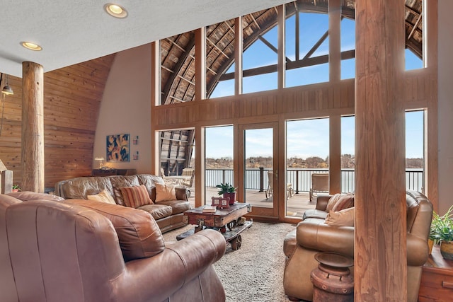 living room featuring high vaulted ceiling, a water view, and recessed lighting