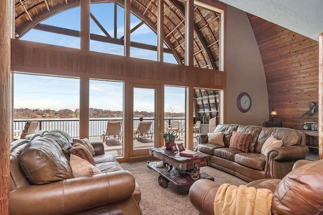 living room with high vaulted ceiling, a water view, carpet, and plenty of natural light