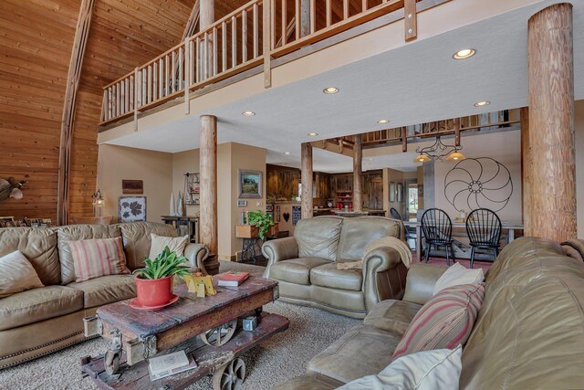 living room featuring wooden walls, ornate columns, a towering ceiling, and recessed lighting