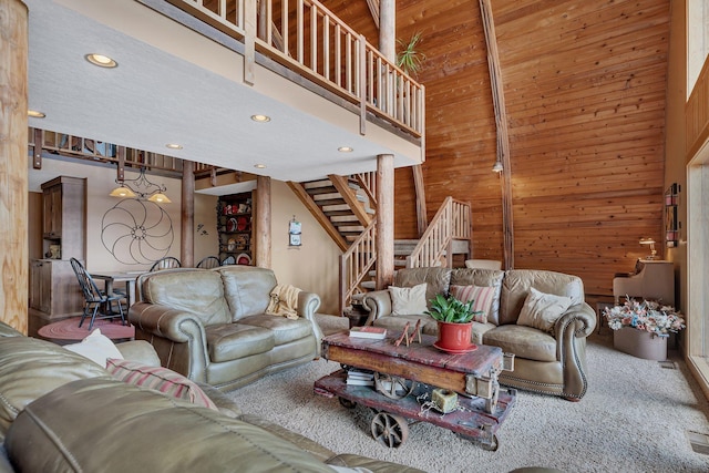 living area with wood walls, recessed lighting, a high ceiling, and stairs