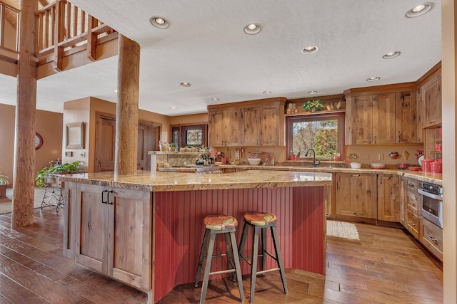 kitchen featuring stainless steel oven, a breakfast bar, and recessed lighting