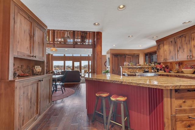 kitchen featuring a kitchen breakfast bar, brown cabinets, recessed lighting, and dark wood-style floors
