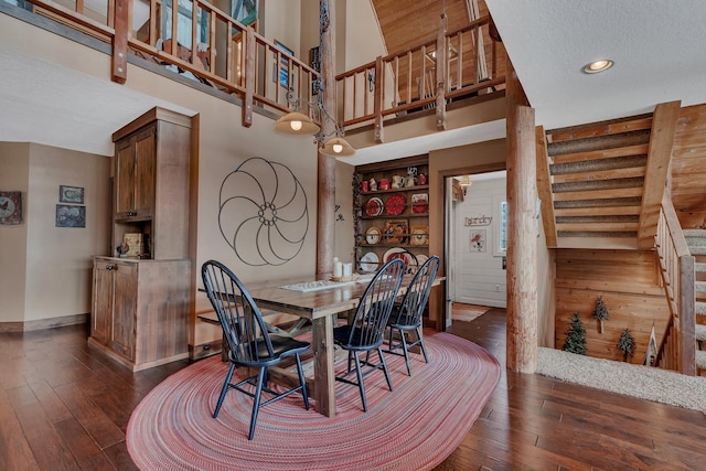 dining space featuring stairway, a towering ceiling, dark wood-style floors, and recessed lighting
