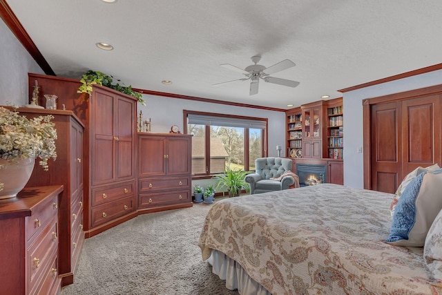 bedroom with recessed lighting, ornamental molding, light colored carpet, and a glass covered fireplace