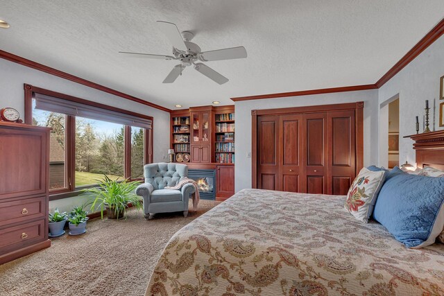 bedroom with carpet floors, crown molding, and a glass covered fireplace