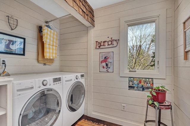 clothes washing area featuring wooden walls, laundry area, and washing machine and dryer