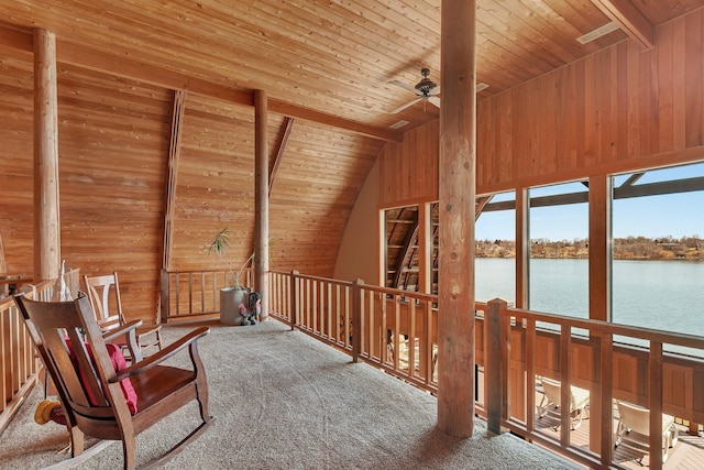 interior space with wooden ceiling, carpet flooring, wooden walls, and a water view