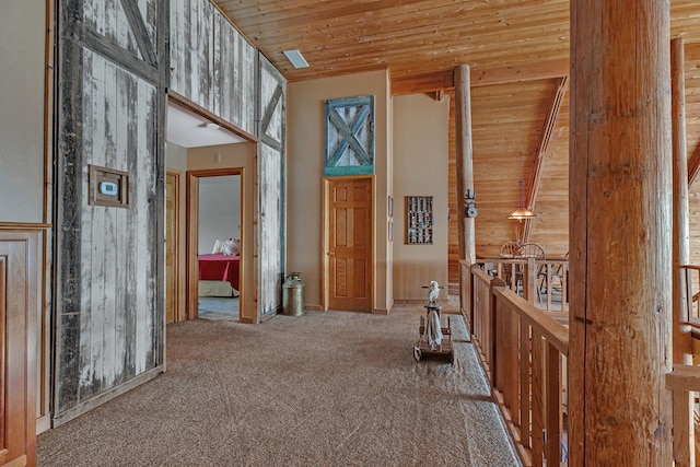 hall featuring wood ceiling, a towering ceiling, wood walls, and carpet