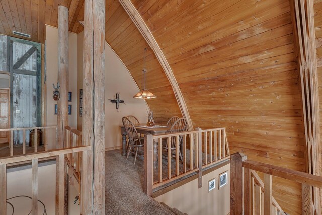 hallway featuring an upstairs landing, lofted ceiling, carpet flooring, and wood ceiling