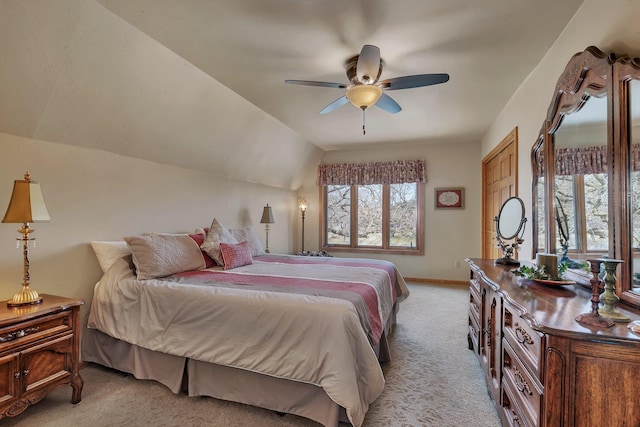 bedroom with ceiling fan, vaulted ceiling, light colored carpet, and baseboards